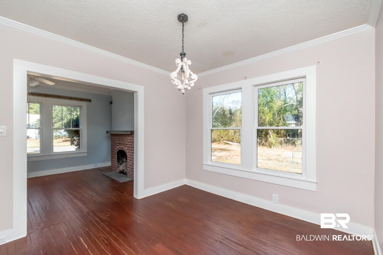731 Jemison Street Mobile, AL 36606 - Photo 3 of 27 Unfurnished living room with dark wood-style floors, a textured ceiling, crown molding, a brick fireplace, and suspended lighting