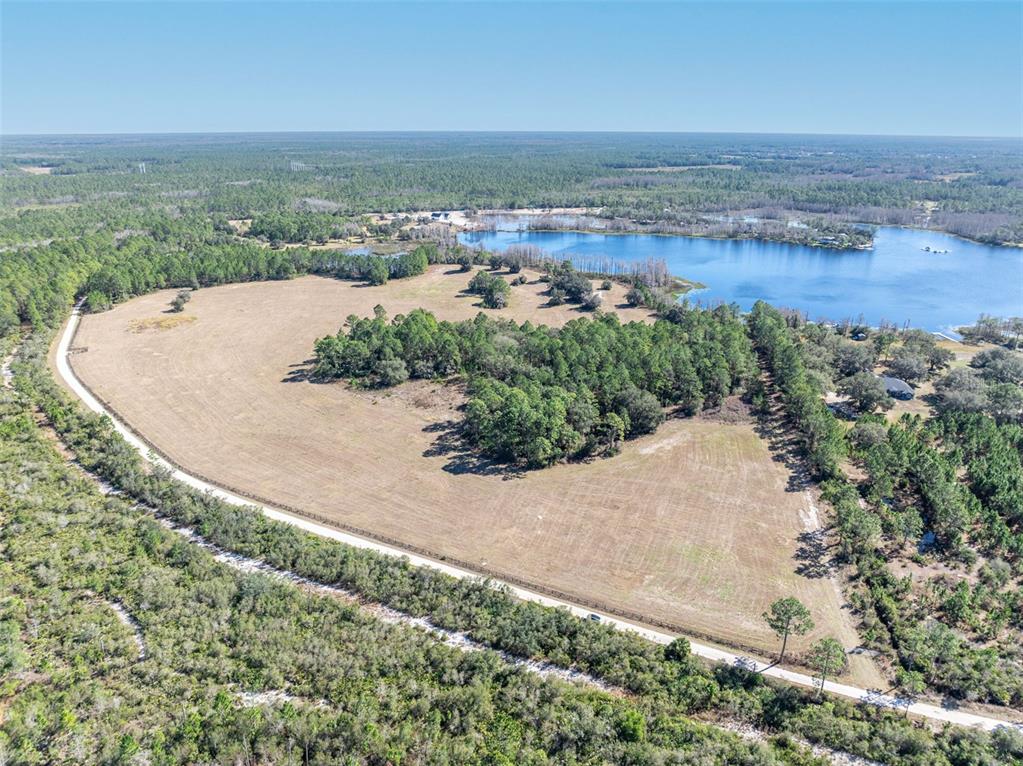 an aerial view of a houses with a yard and lake view