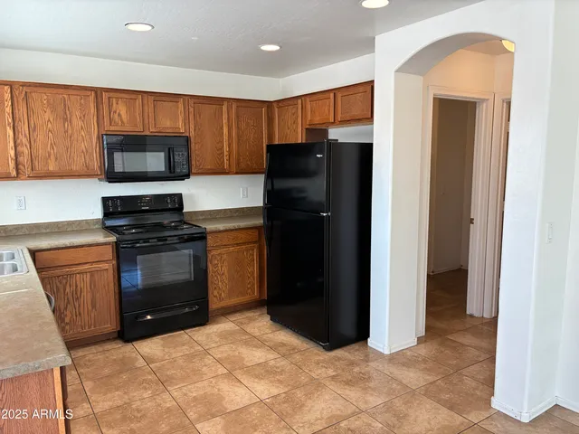 a kitchen with granite countertop a refrigerator and a stove top oven
