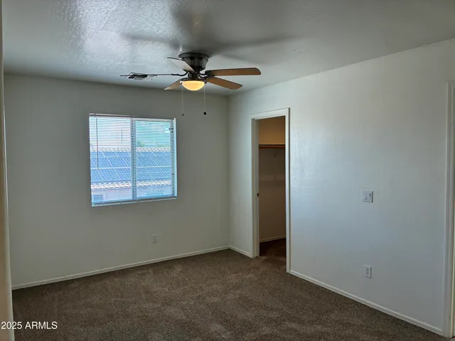 an empty room with a ceiling fan and a window