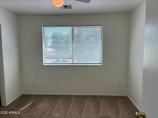 a view of an empty room with closet and a window