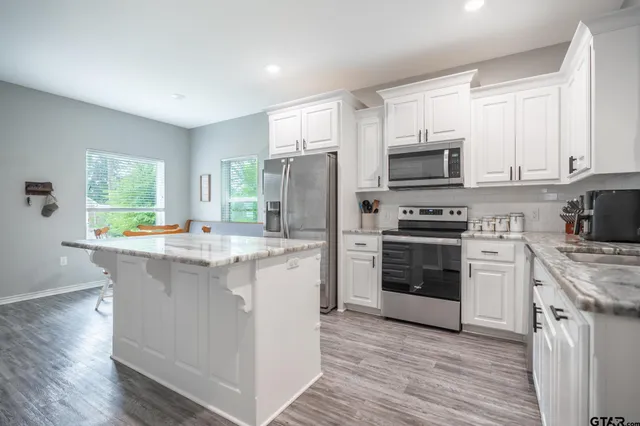 a kitchen with kitchen island granite countertop a sink cabinets and stainless steel appliances