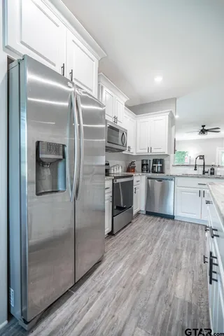 a kitchen with kitchen island a counter top space a refrigerator cabinets and a sink