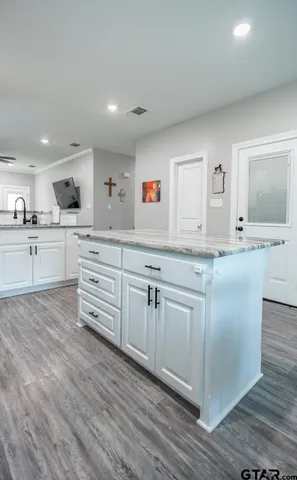 a kitchen with granite countertop a sink cabinets and wooden floor