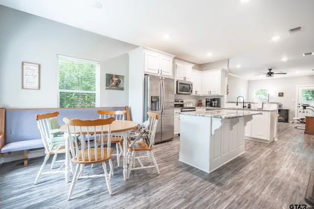 a dining room with kitchen island stainless steel appliances furniture a dining table and chairs