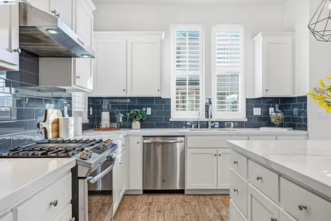 a kitchen with stainless steel appliances granite countertop a stove a sink and white cabinets