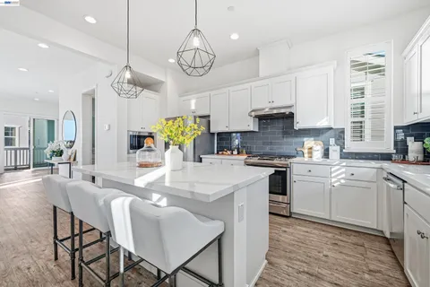 a kitchen with stainless steel appliances granite countertop a stove a sink dishwasher a dining table and chairs with wooden floor