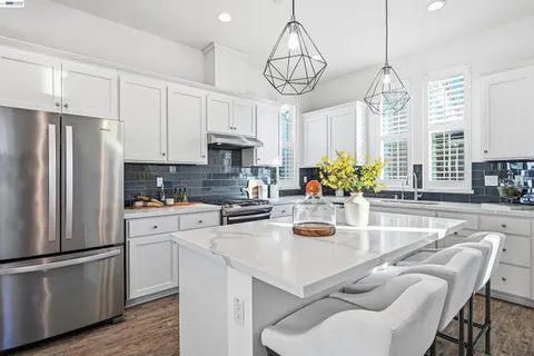 a kitchen with stainless steel appliances granite countertop a sink a stove and a refrigerator