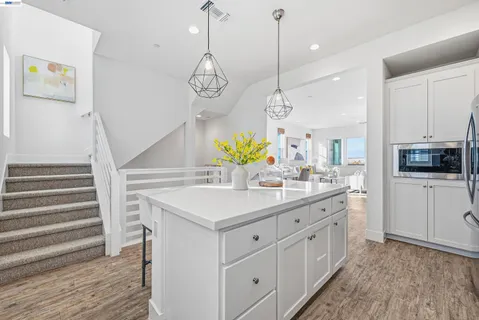 a kitchen with a sink dishwasher a dining table and chairs with wooden floor