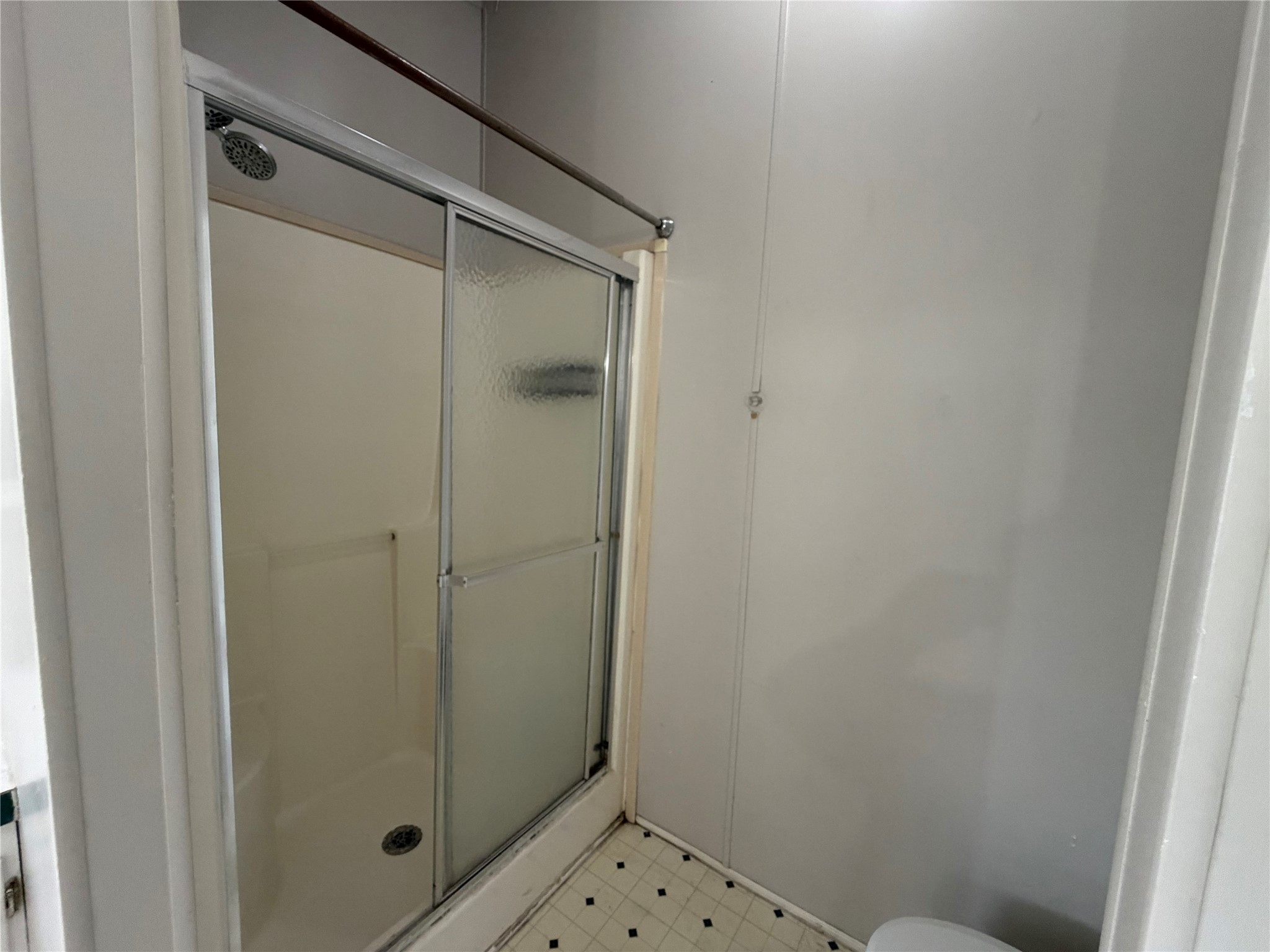 12609 Dessau Road, Unit 410 Austin, TX 78754 - Photo 10 of 11 Shower enclosure with sliding frosted glass doors, a built-in shower seat, and a chrome shower head