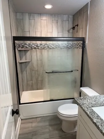 a bathroom with a granite countertop sink a toilet a mirror and shower