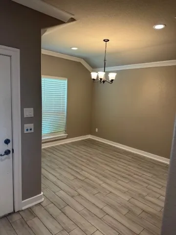 an empty room with wooden floor mirror and windows