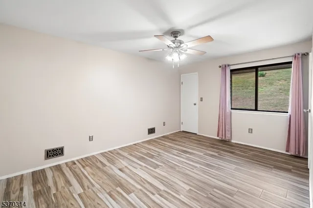 a view of an empty room with a window and a ceiling fan