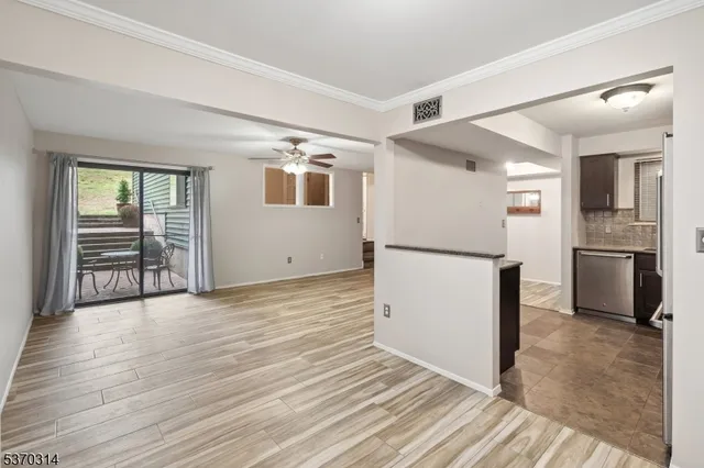 an empty room with wooden floor and a kitchen view