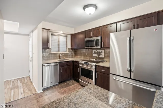 a kitchen with stainless steel appliances granite countertop a refrigerator stove a sink and dishwasher