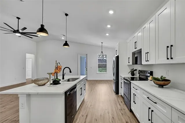 a kitchen with kitchen island granite countertop a sink a counter space appliances and cabinets
