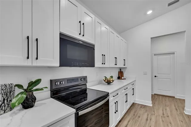 a kitchen with microwave a stove and cabinets