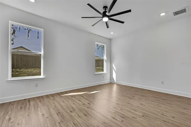 a view of an empty room with a window and wooden floor