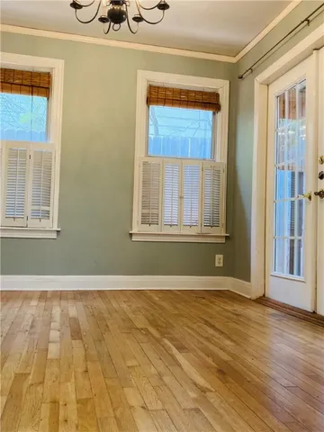 an empty room with wooden floor closet and windows