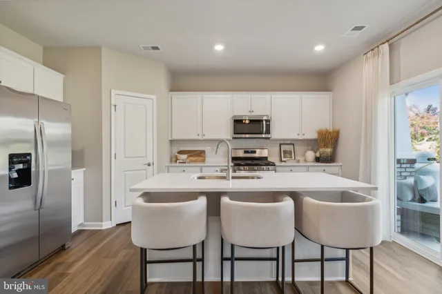 a kitchen with stainless steel appliances granite countertop a table chairs microwave and refrigerator
