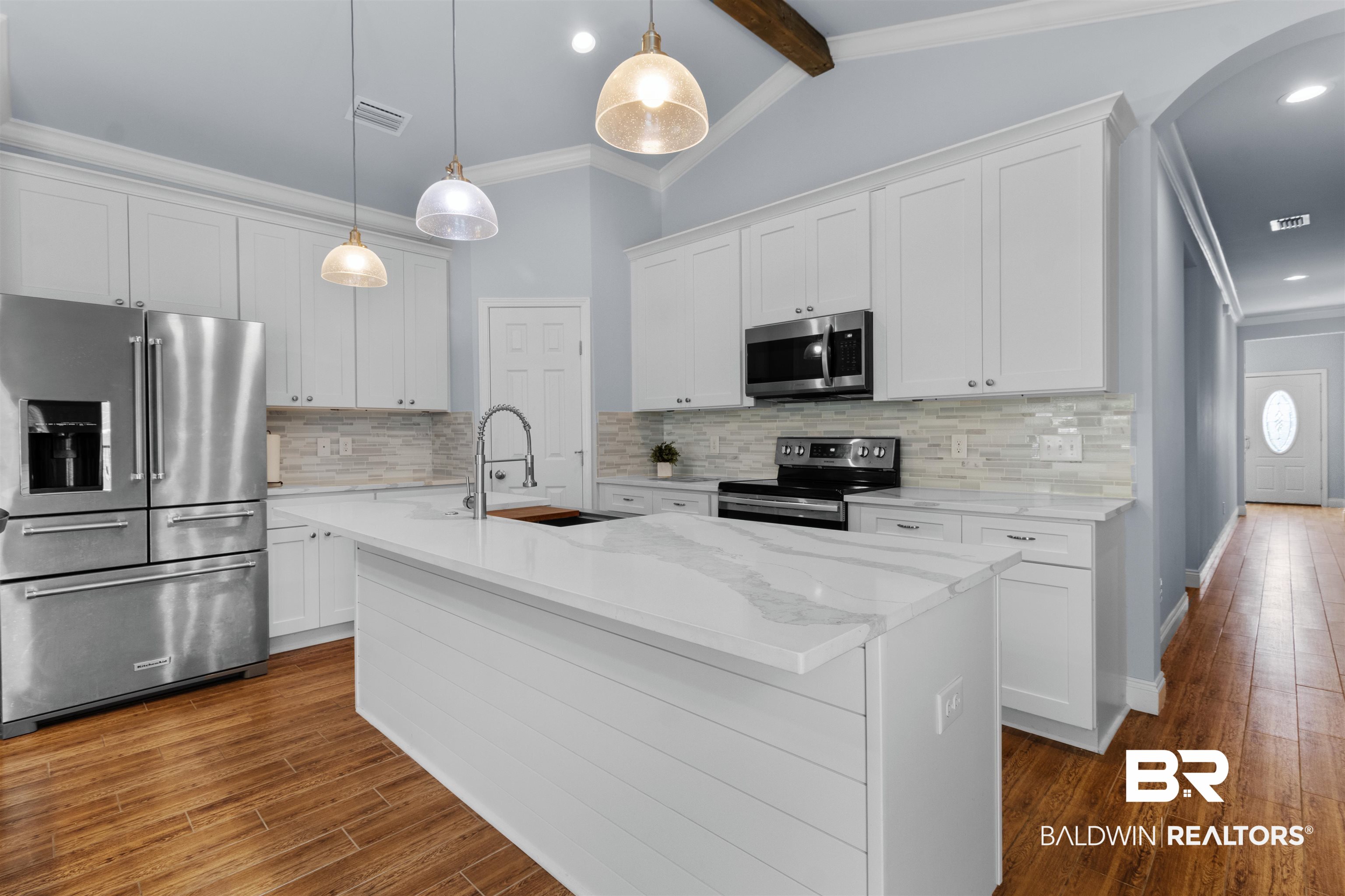 927 Periwinkle Lane Foley, AL 36535 - Photo 2 of 26 Kitchen featuring a central island with a white countertop and shiplap-style paneling, stainless steel appliances, white cabinetry, a tile backsplash, and wood-finish flooring