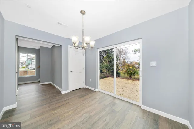 a view of a big room with wooden floor chandeliers and kitchen view