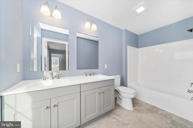 a bathroom with a double vanity sink toilet mirror and bathtub