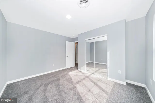 a view of an empty room with window and closet