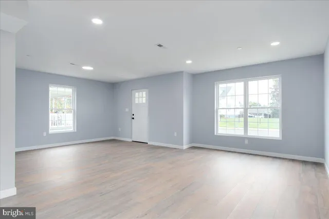 a view of an empty room with wooden floor and window