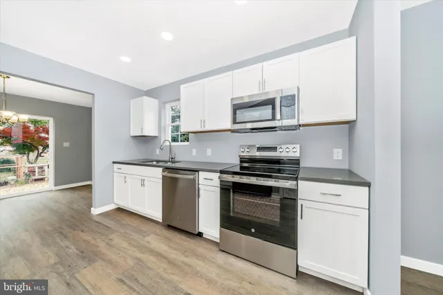 a kitchen with cabinets stainless steel appliances and wooden floor