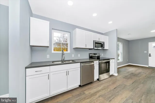 a kitchen with granite countertop white cabinets and stainless steel appliances