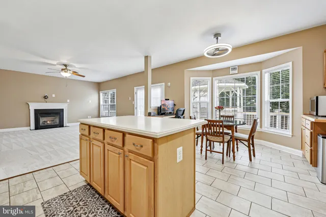 a kitchen with stainless steel appliances granite countertop a stove a sink a dining table and chairs with wooden floor