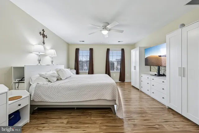 a spacious bedroom with a large bed a chandelier and dresser