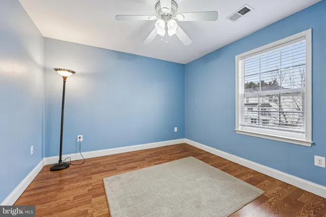 a view of an empty room with window and chandelier fan
