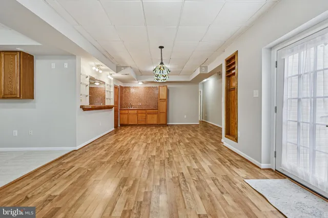 a big room with wooden floor chandelier and windows