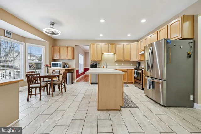 a kitchen with stainless steel appliances granite countertop a stove a refrigerator a dining table and chairs with wooden floor