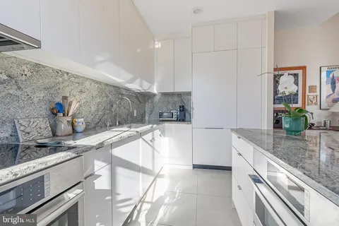 a kitchen with stainless steel appliances granite countertop a sink and white cabinets
