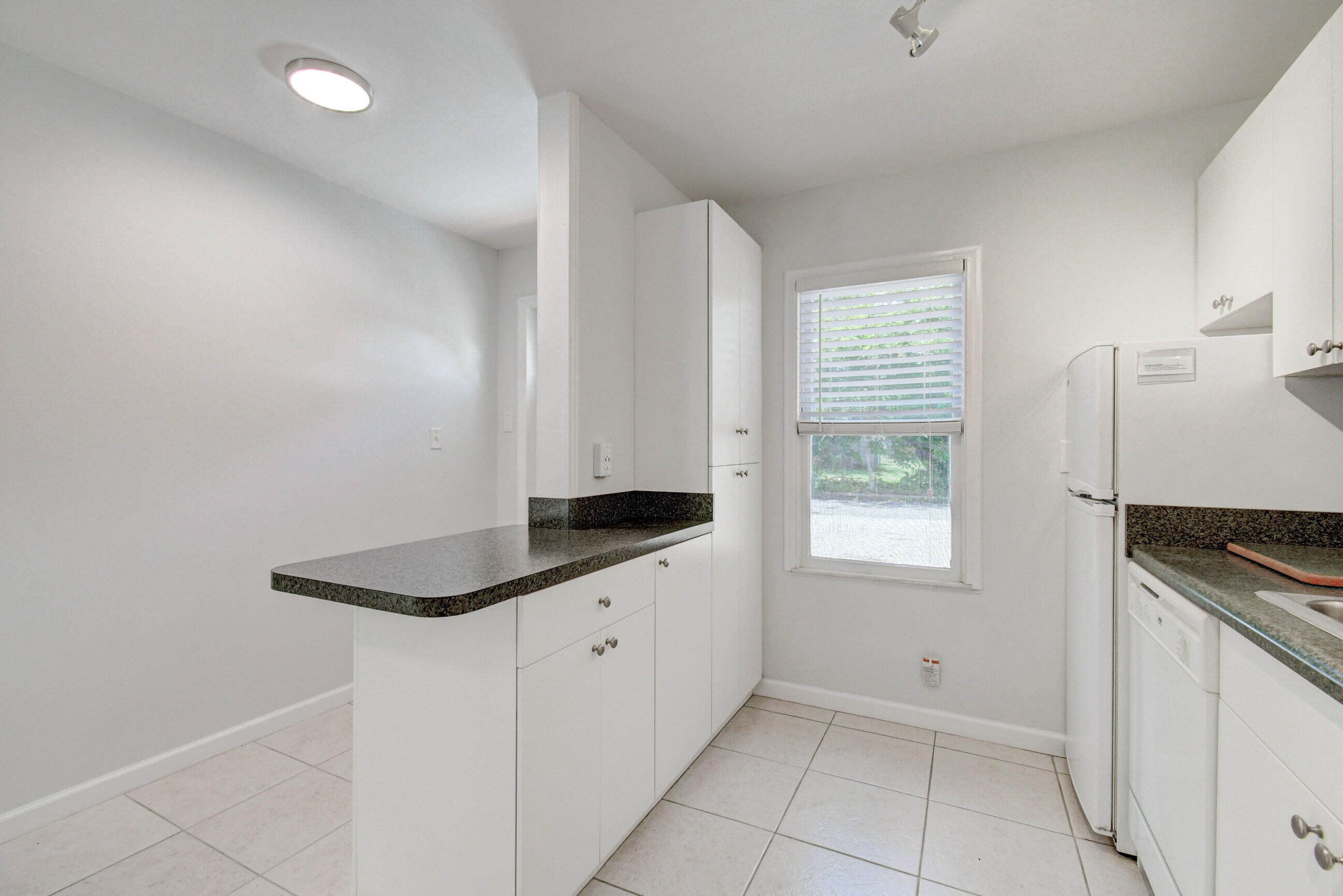 4 Gibbs Road, Unit 1 Boynton Beach, FL 33435 - Photo 13 of 43 a kitchen with granite countertop white cabinets and white appliances