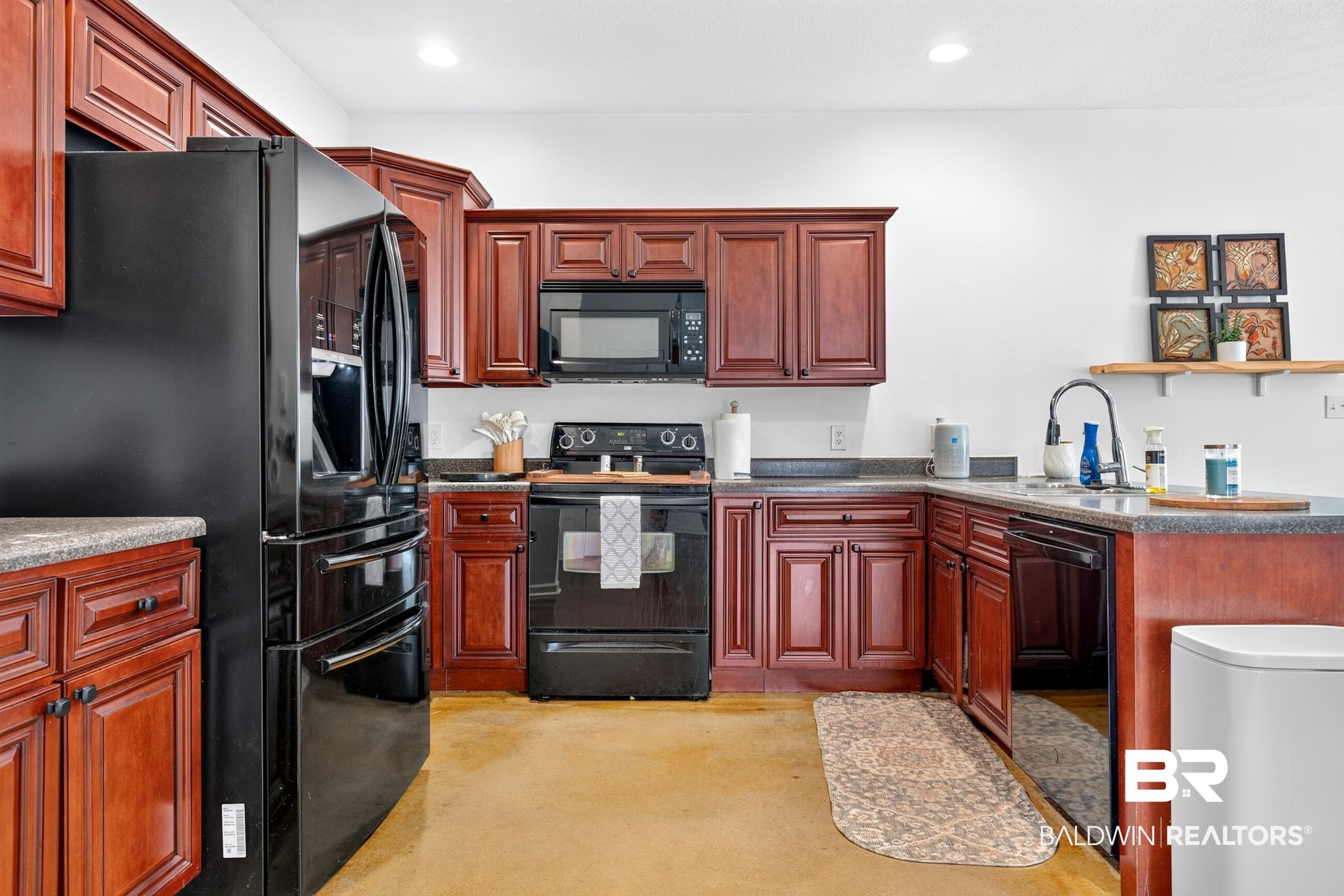 17419 Lewis Smith Drive Foley, AL 36535 - Photo 16 of 38 Kitchen featuring rich wood cabinetry, dark countertops, and black appliances including a refrigerator, range, microwave, and dishwasher