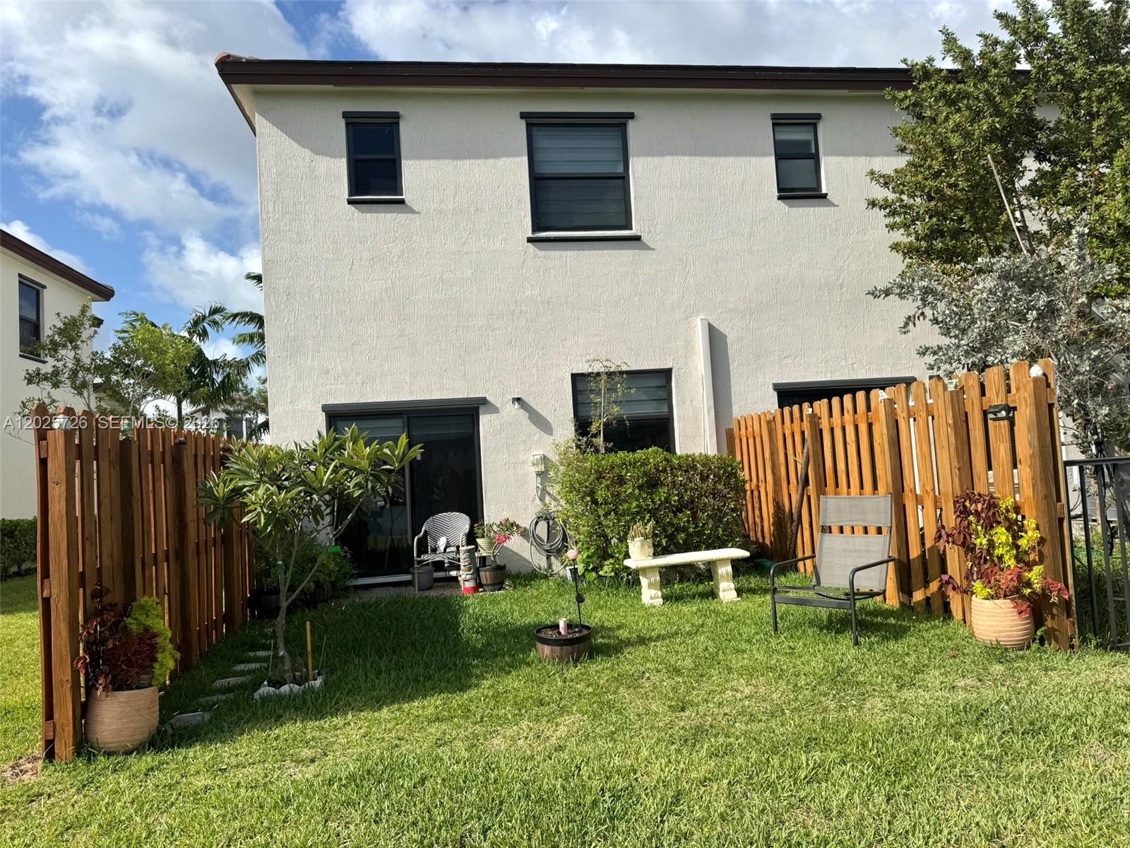 10020 Southwest 228th Terrace Miami, FL 33190 - Photo 19 of 22 a garden with a bench in front of the house