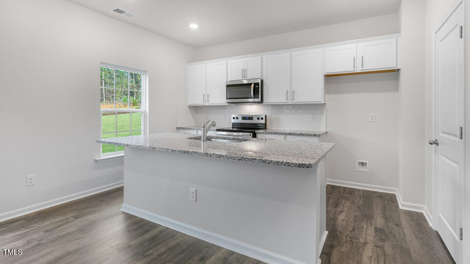 73 Stone Apiary Drive Angier, NC 27501 - Photo 7 of 32 a kitchen with granite countertop a sink cabinets a window and stainless steel appliances
