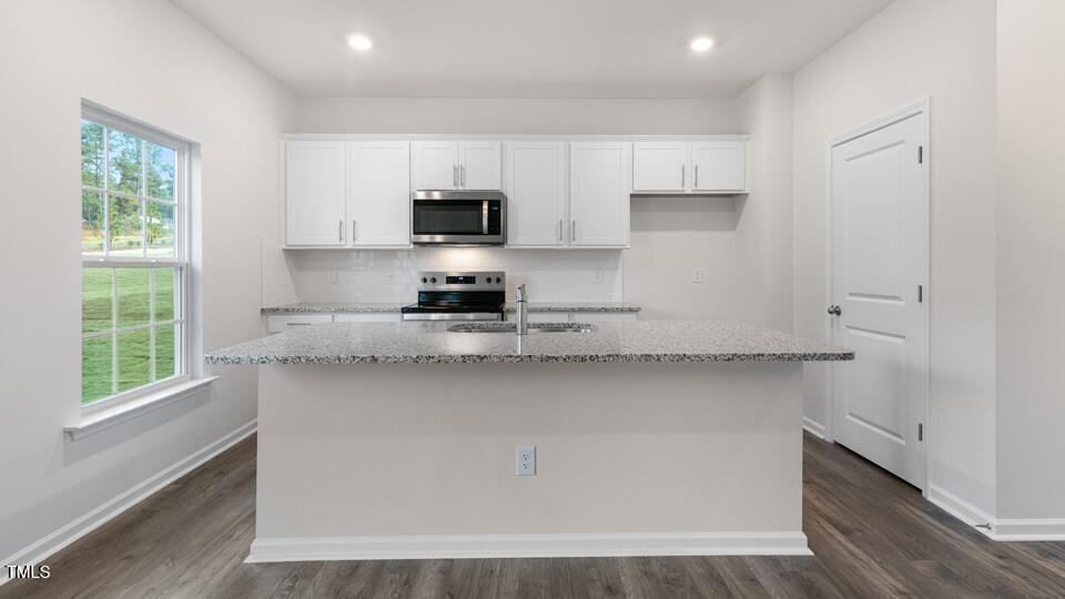 73 Stone Apiary Drive Angier, NC 27501 - Photo 9 of 32 a kitchen with stainless steel appliances a sink a stove a microwave and cabinets