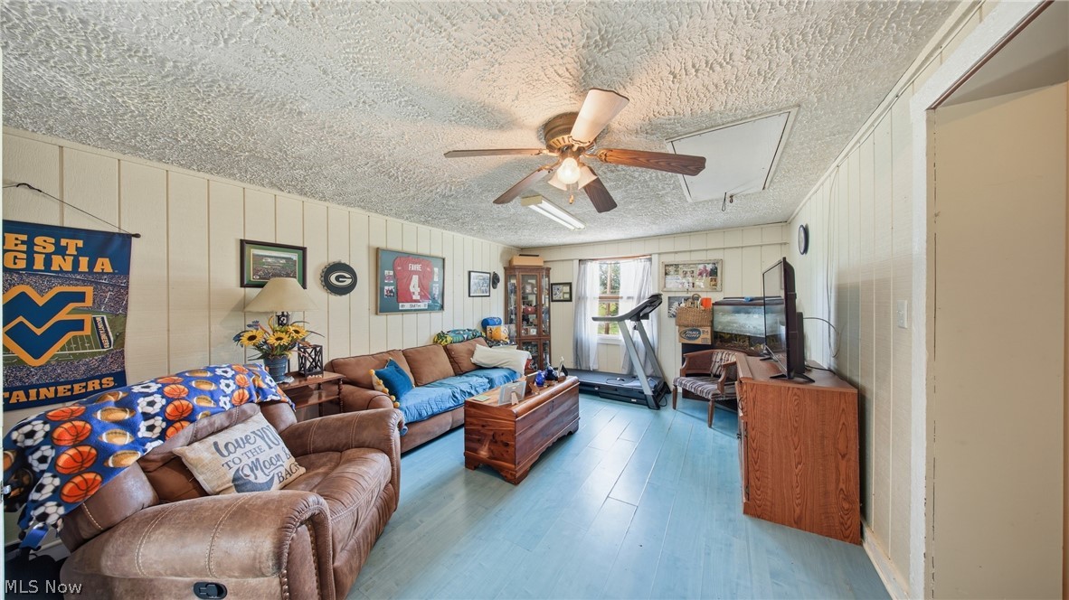 89 Dagg Road Parkersburg, WV 26101 - Photo 22 of 45 Spacious living area featuring light blue wood-finish flooring, white vertical wall paneling, and a textured ceiling