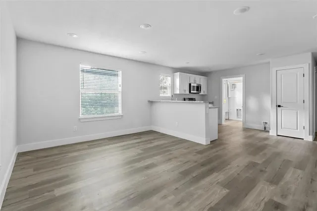 a view of a kitchen with wooden floor electronic appliances and window