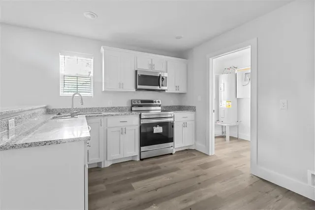 a kitchen with granite countertop a stove a sink and a microwave