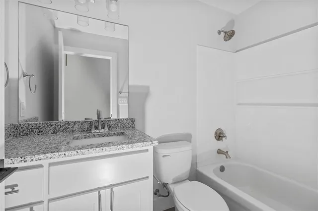 a bathroom with a granite countertop sink toilet and shower