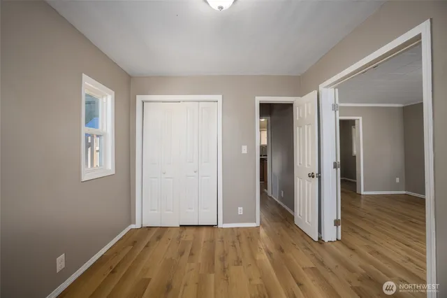 a view of an empty room with wooden floor and a window