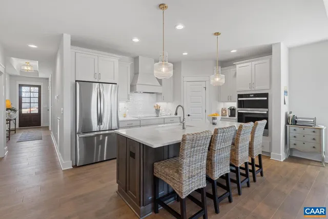 a kitchen with stainless steel appliances kitchen island granite countertop a table chairs microwave and refrigerator