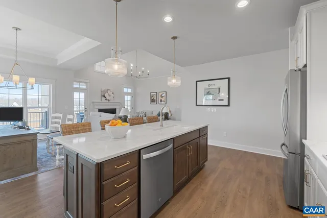 a kitchen with a stove a sink a center island and a wooden floor