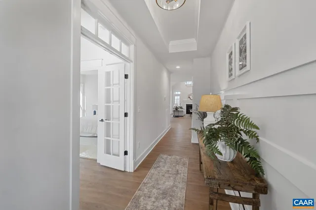 a hallway with white doors wooden floor and a chandelier